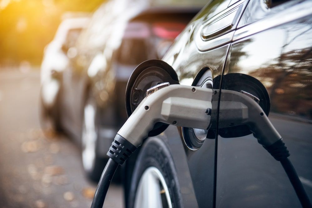 Close-up of electric vehicle charging cable plugged in at home station, everyday reality of owning or leasing an EV in 2026