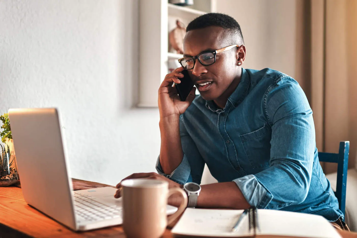 Person at home using laptop and phone to compare different car insurance quotes, everyday scene showing a practical way to reduce expensive electric vehicle insurance costs