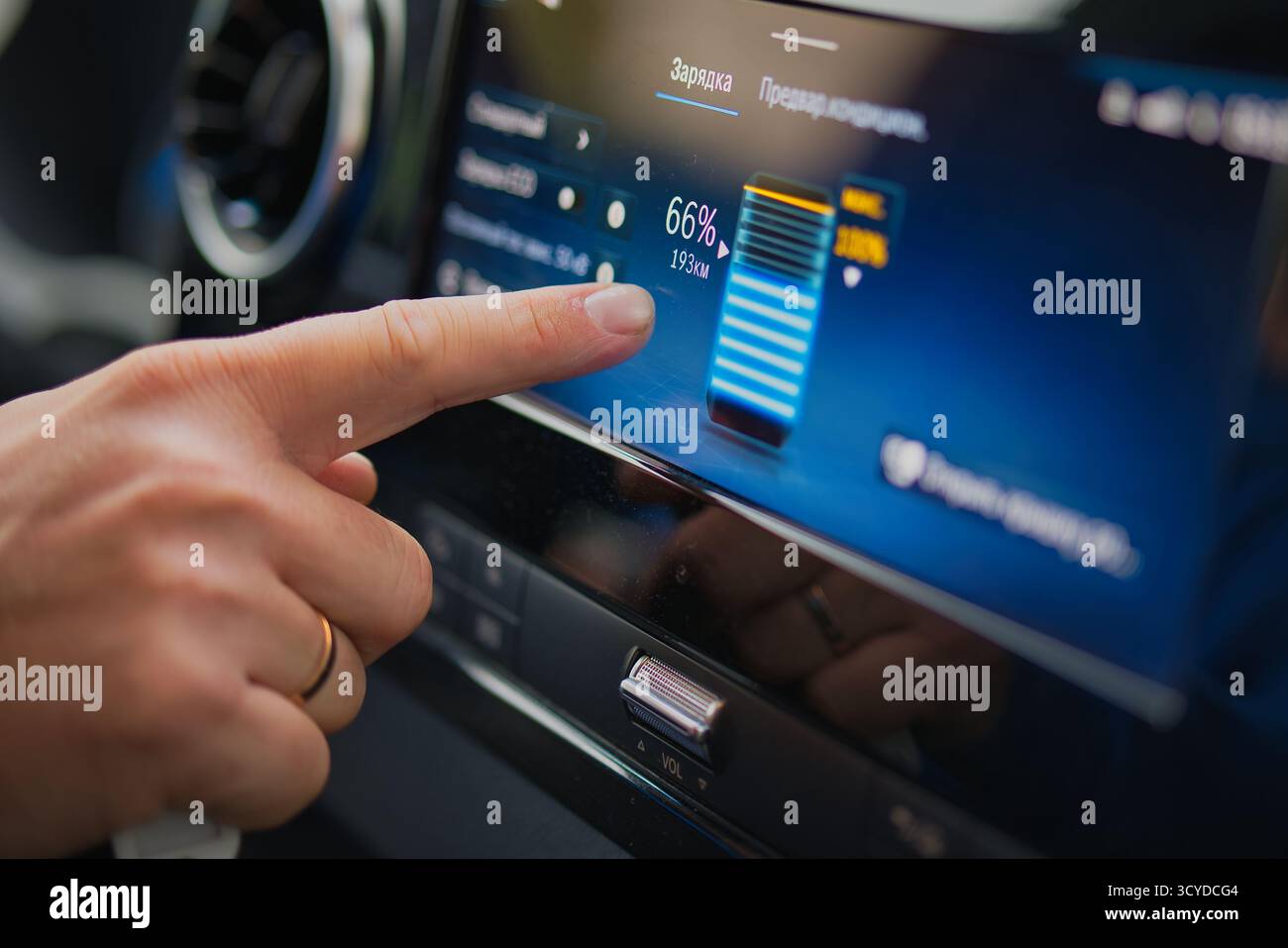 Close-up view of a hand touching an electric car touchscreen showing battery charge level and remaining range, a common way owners track EV battery health over time.