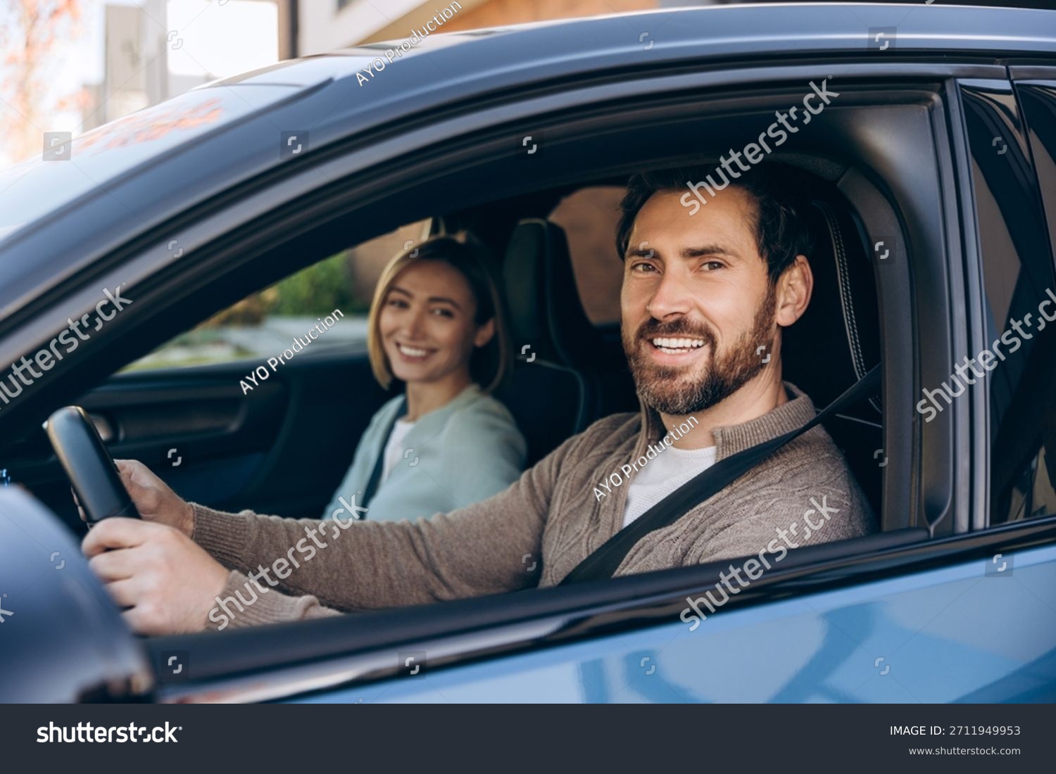 Happy couple driving their modern electric car on a scenic road, enjoying ownership after weighing lease vs buy EV decision in 2026