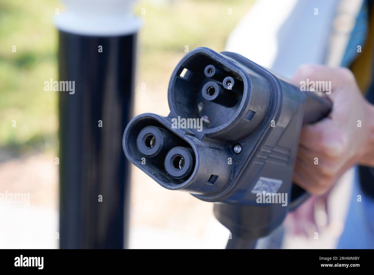 Real life close-up of a hand holding a CCS Combo 1 charging connector, ready for fast DC charging at an electric vehicle station