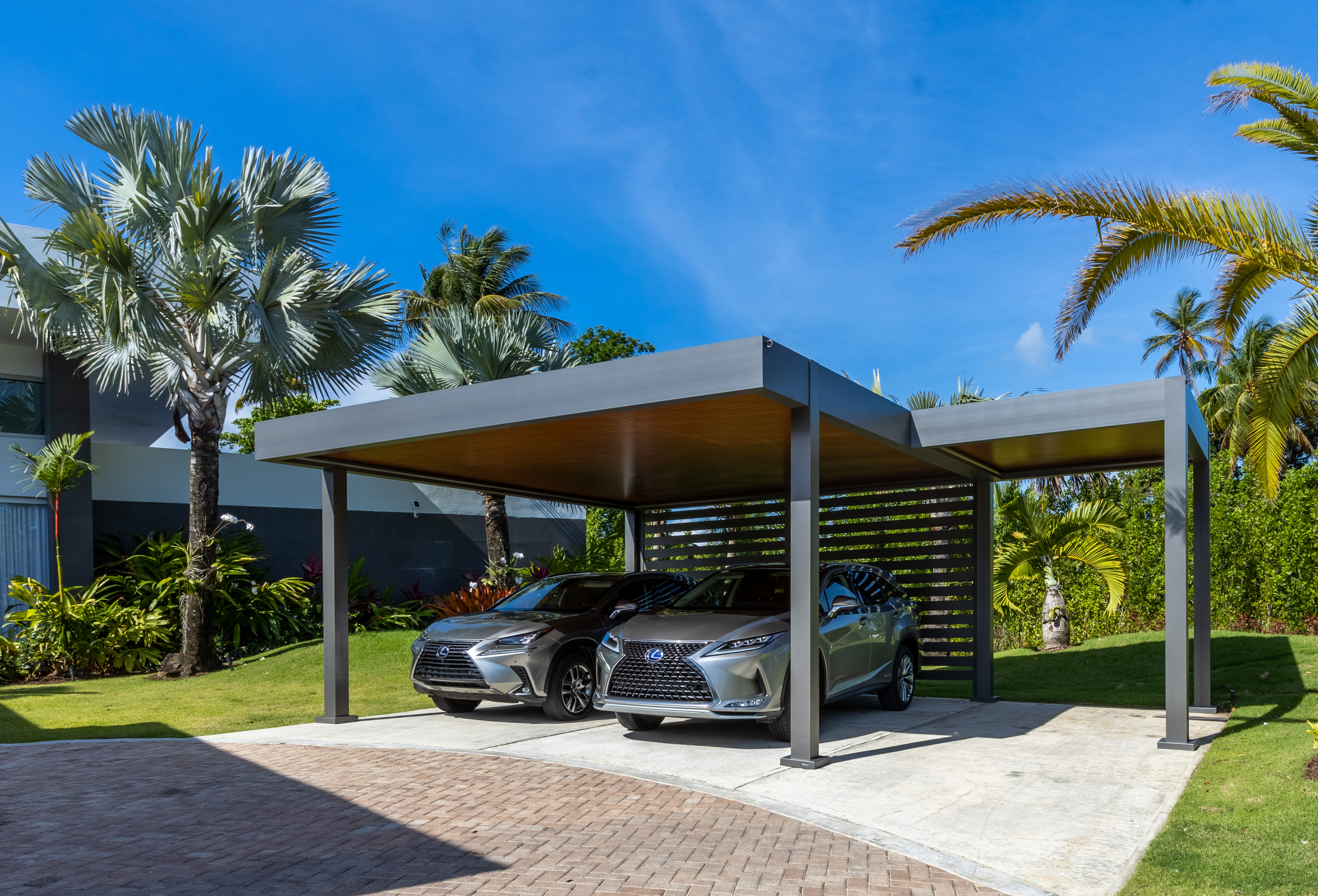 Electric cars parked under a shaded carport on a sunny day, real photo showing protection from extreme heat to prolong EV battery lifespan
