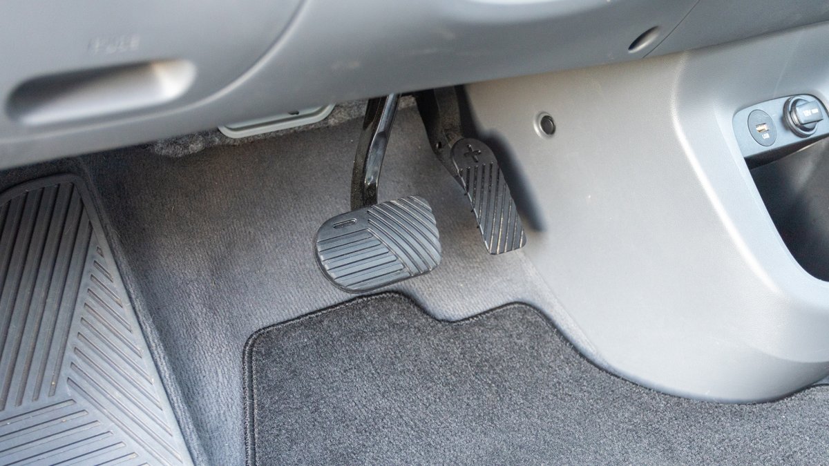Close-up real life photo of accelerator and brake pedals inside an electric car, showing the foot position used for one-pedal driving and regenerative braking control