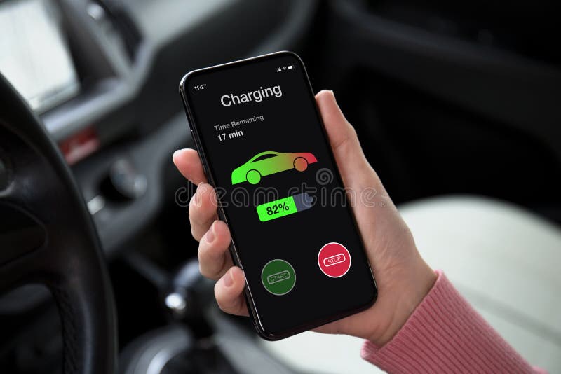 Person holding phone showing EV charging app progress while charging their Tesla at home with Wall Connector