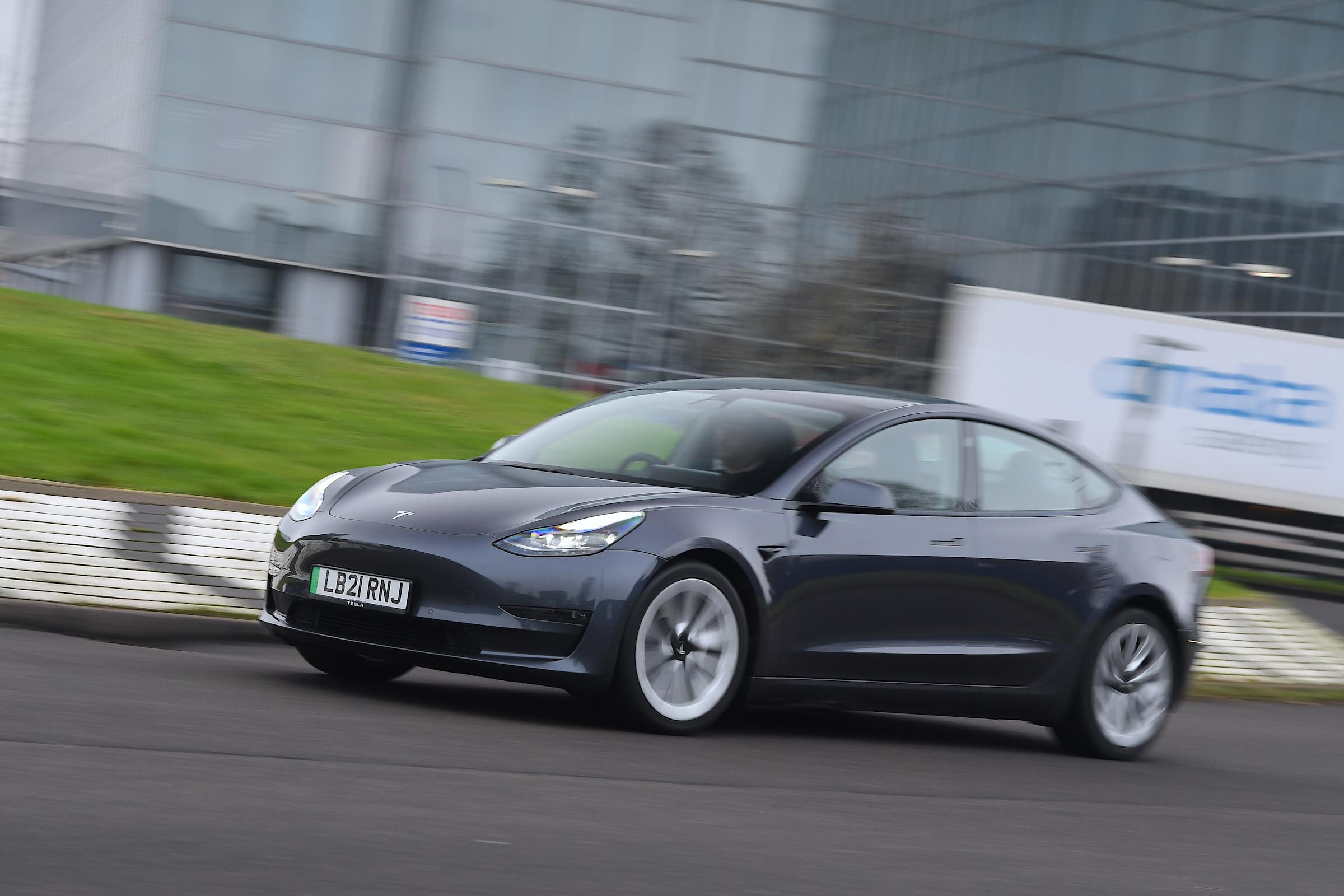A dark gray Tesla Model 3 driving on a track, highlighting the performance and reliability that make it one of the most reliable used EVs to buy in 2026