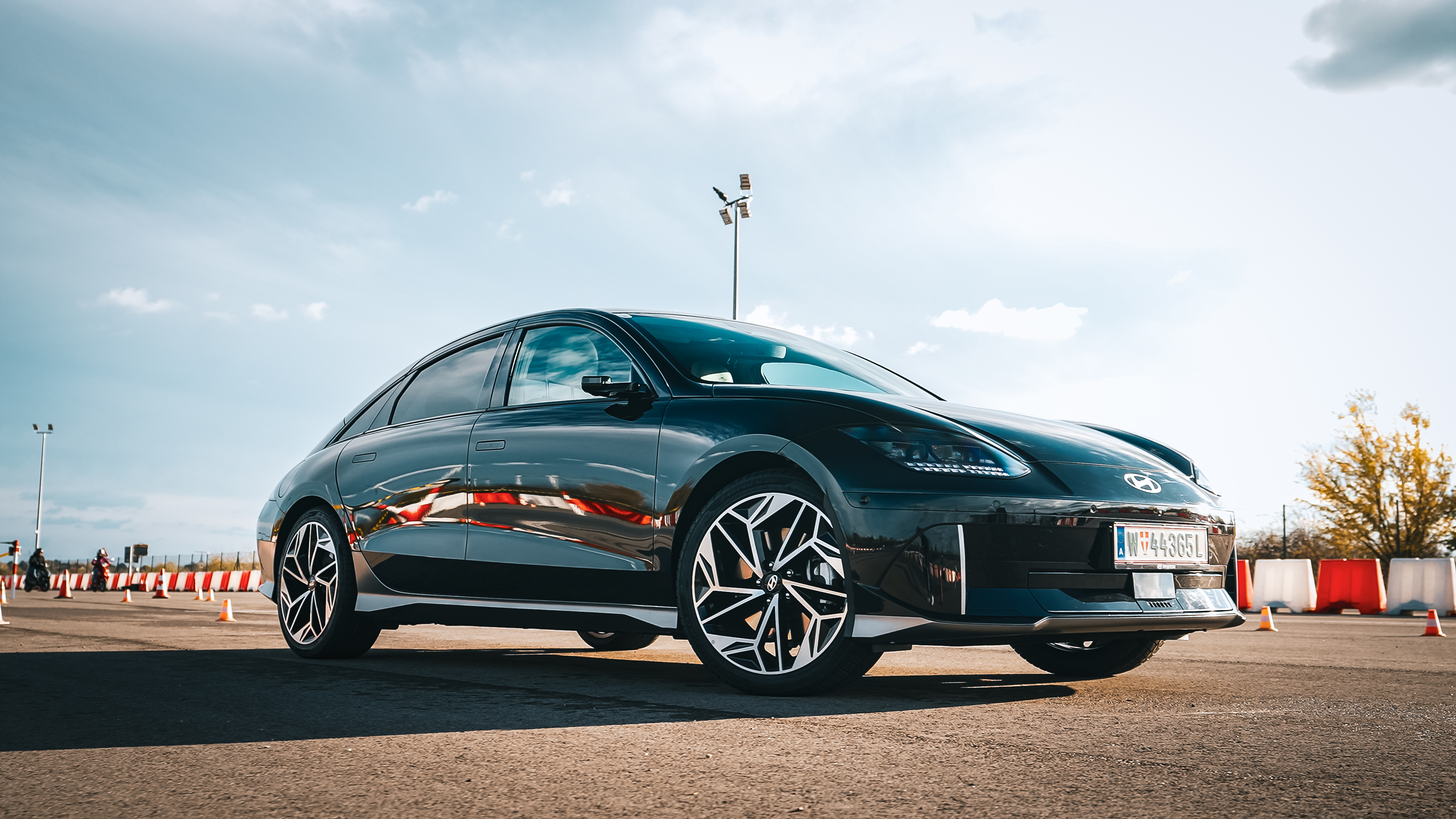 Black Hyundai IONIQ 6 parked outdoors under a cloudy sky in a real-life setting, highlighting its unique curved aerodynamic design for the Model 3 vs IONIQ 6 efficient electric sedan comparison