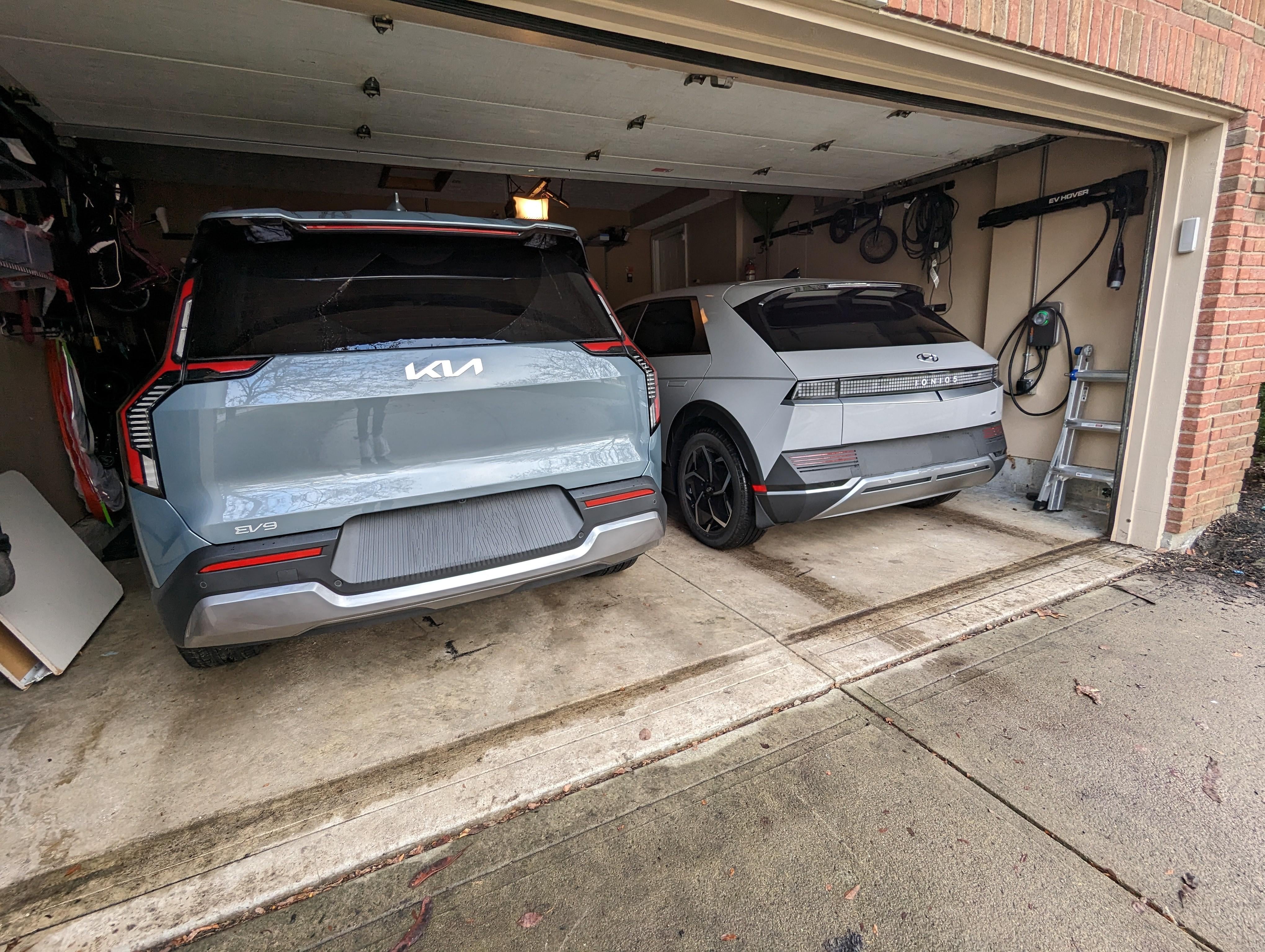 Two modern electric vehicles parked in a home garage with charging stations, representing the satisfaction of owning EVs after claiming the federal tax credit in 2026