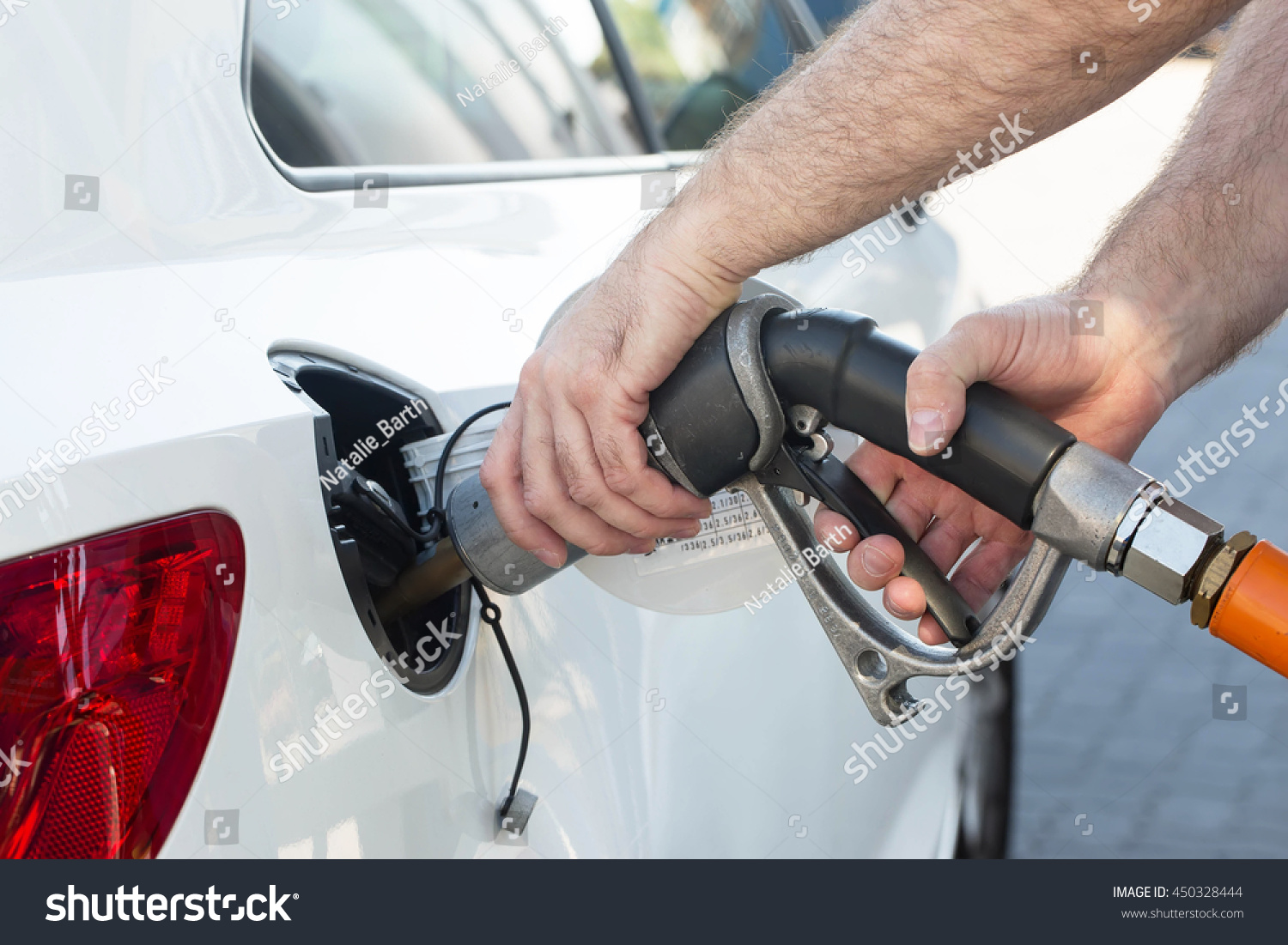 Real person filling up a gas car at a station with visible fuel prices, capturing the routine expense in a real-world gas vs electric cost comparison