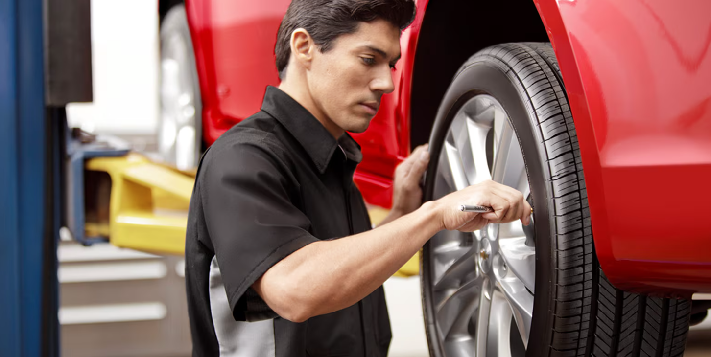 Person carefully checking tire pressure on a vehicle wheel in a garage, emphasizing proper maintenance for specialized tires on electric cars