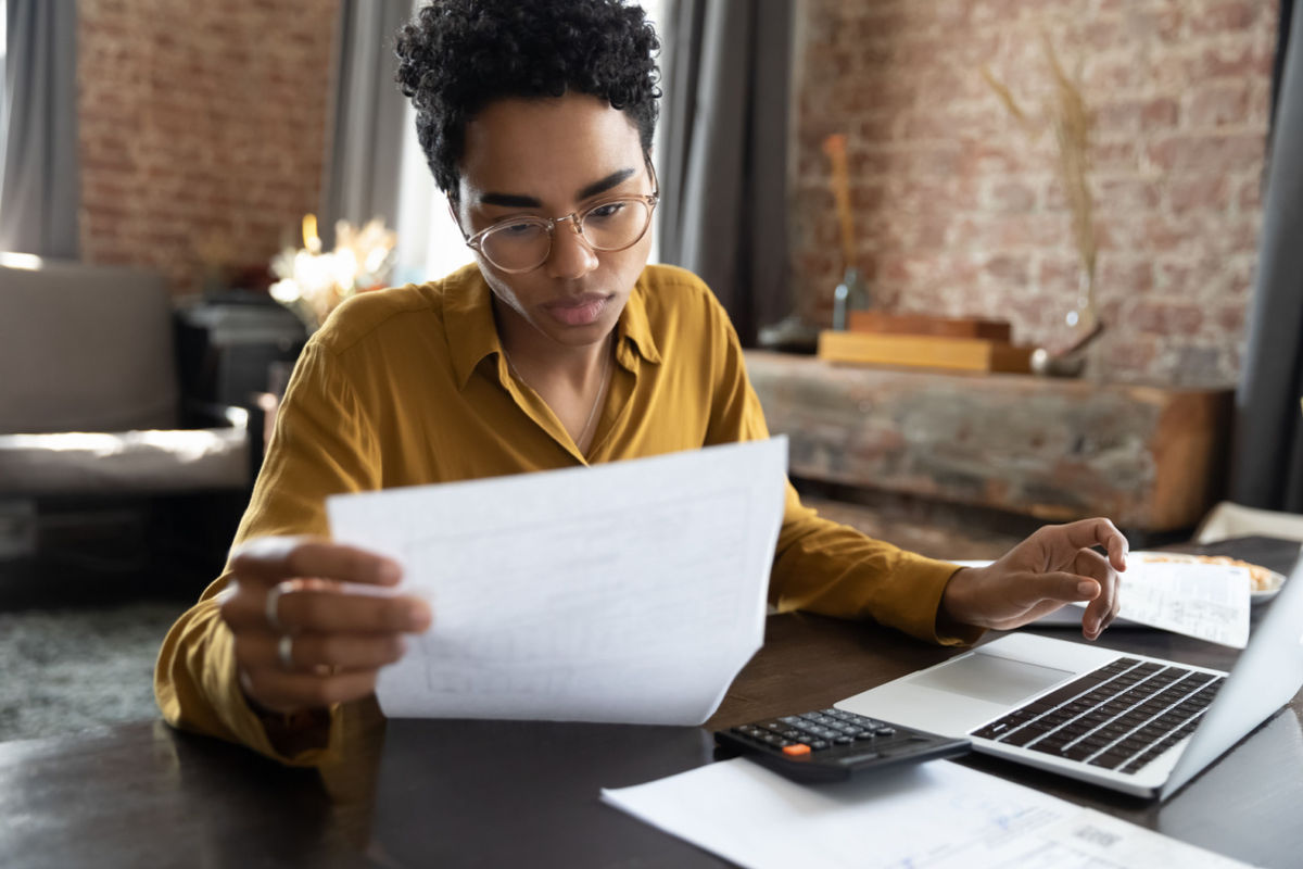 Person at home calculating monthly costs and finances for leasing vs buying an electric vehicle in 2026 on laptop with calculator
