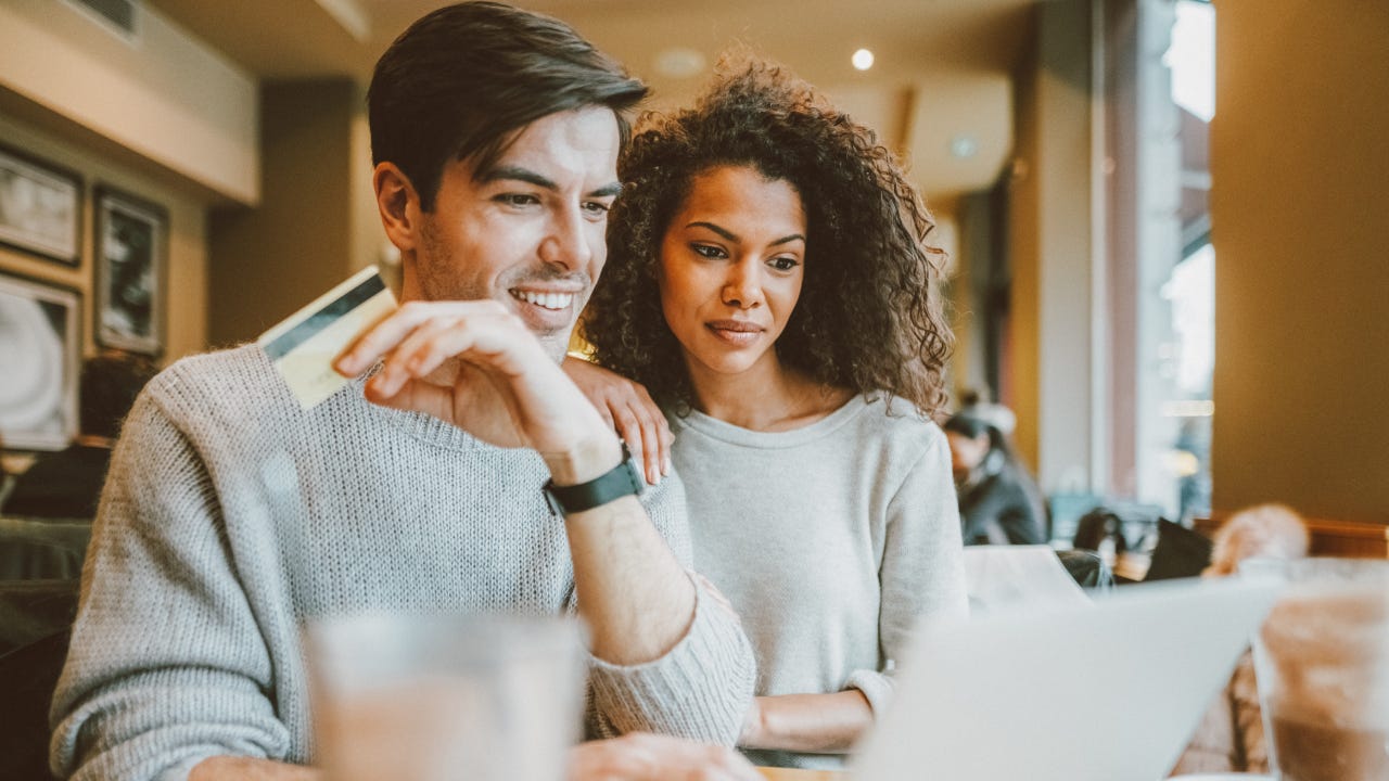 Couple happily discussing finances over coffee, representing the smart planning behind getting the best auto loan rates for electric vehicles