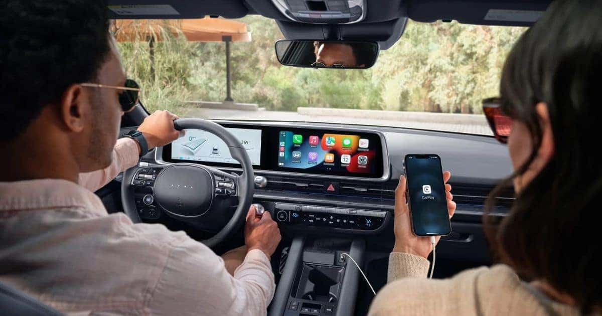 Hyundai IONIQ 6 interior with two people inside, large dual screens and modern cabin in natural light, real-life comfort for efficient electric sedan comparison with Tesla Model 3