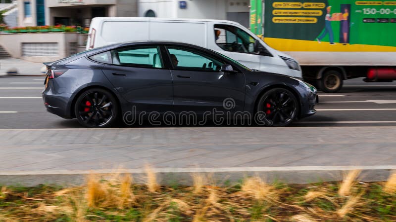 Gray Tesla Model 3 electric car in motion on a city road, demonstrating how specialized EV tires provide better grip, quieter ride, and improved range in everyday driving