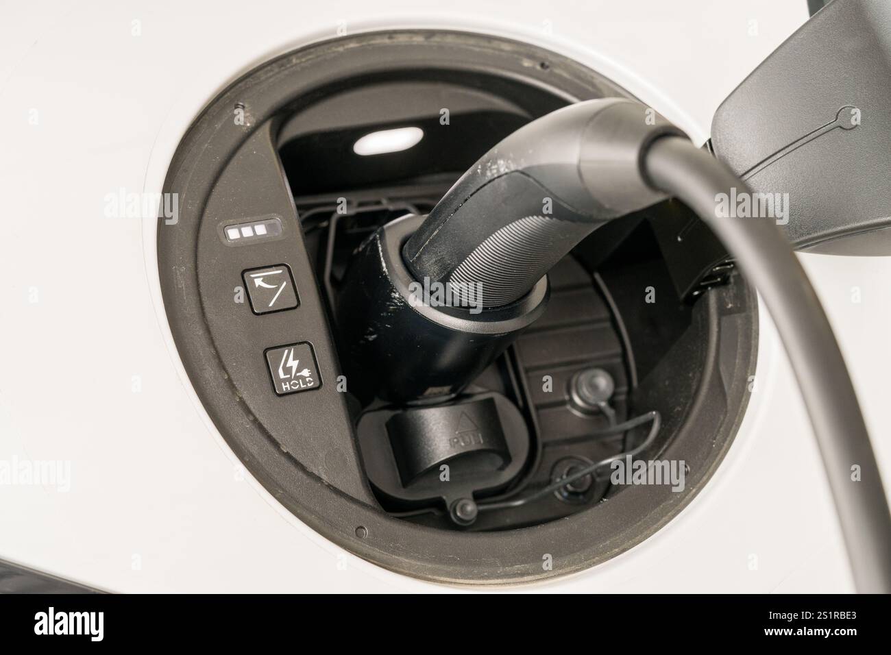 Close-up real photo of a J1772 charging connector plugged into an electric vehicle port during a level 2 home charging session