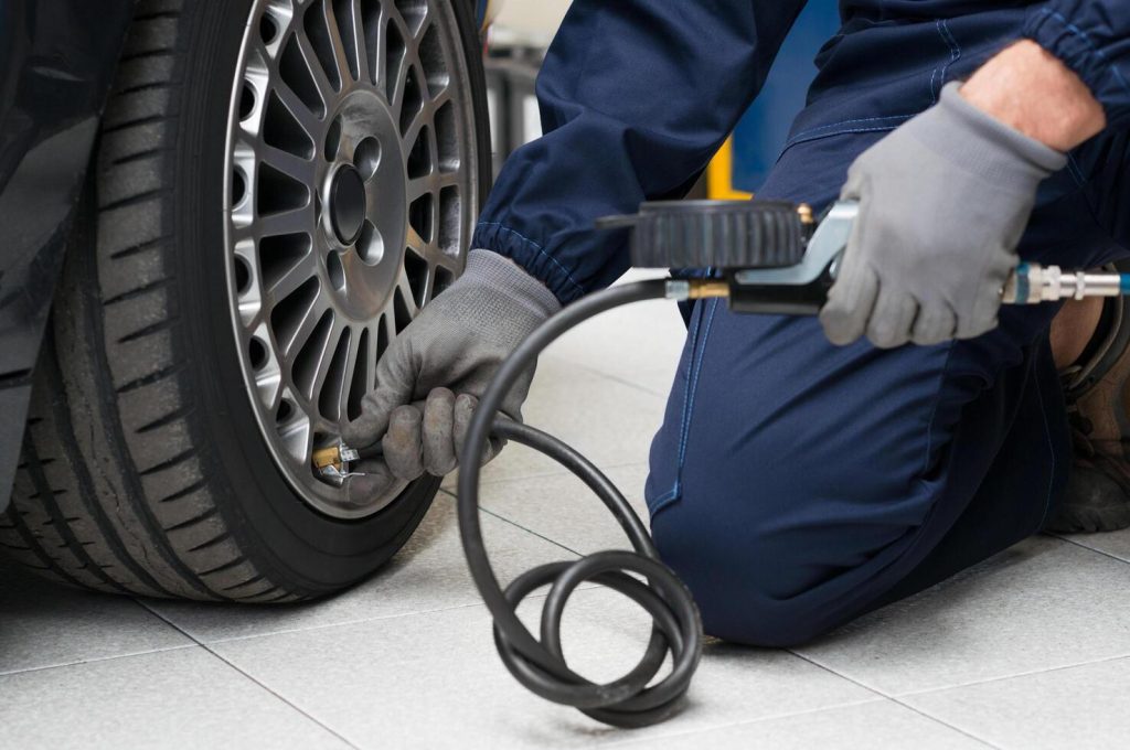 Person checking tire pressure on a vehicle in a real-life setting, essential maintenance tip to help extend electric car battery life