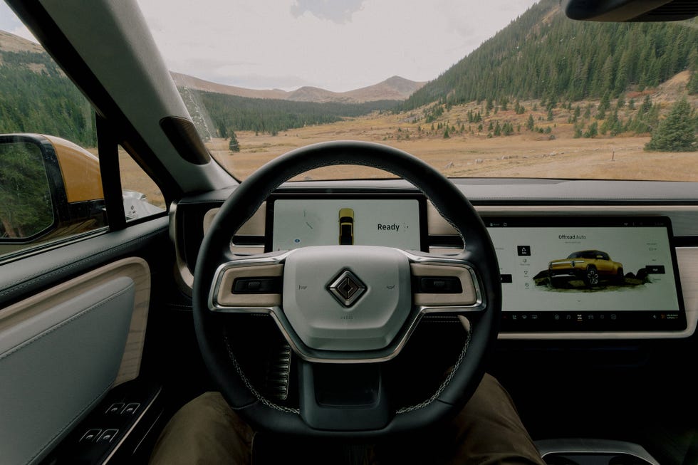 Driver's view inside the Rivian R1T with modern dashboard and off-road mode selected, emphasizing the tech-forward cabin of this electric pickup truck