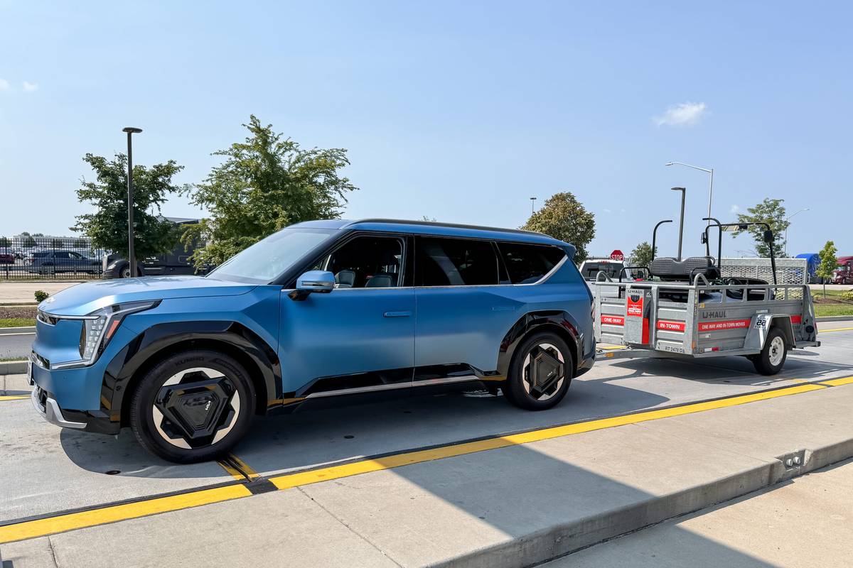 Kia EV9 electric SUV towing a loaded trailer in a parking lot, highlighting how modern electric SUVs balance towing capacity with everyday practicality and decent range even when loaded.